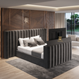Modern bedroom with a gray upholstered bed and wooden wall paneling. TV Bed With oversize headboard.