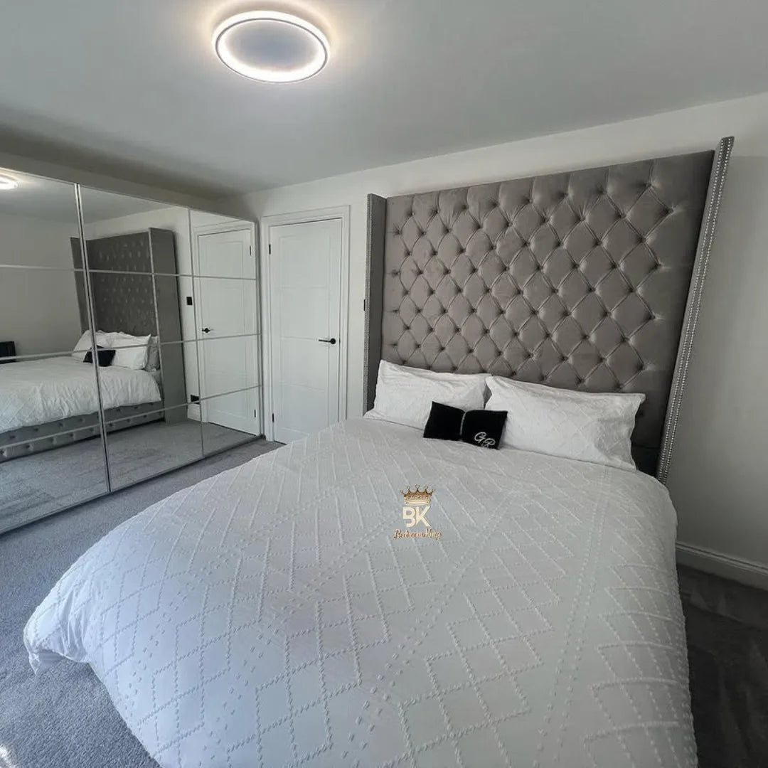 Bedroom with a tufted headboard and mirror reflecting the room.